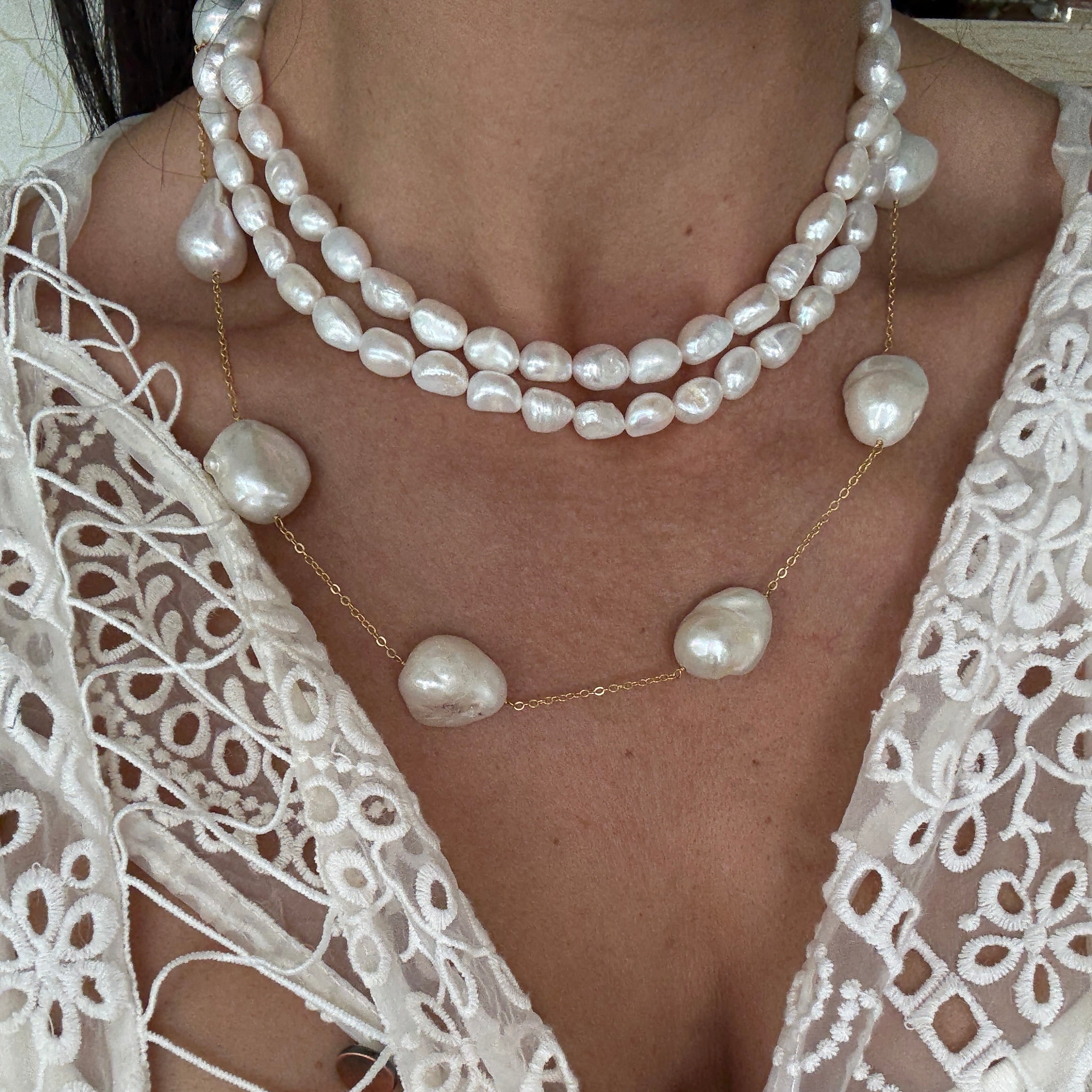 Pearl necklace and bracelet on a person wearing a white lace garment